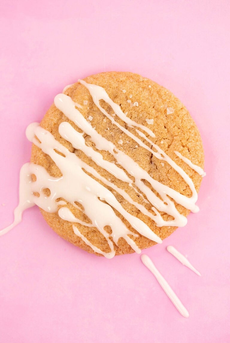 Gorgeous gingerbread cookie drizzled with a glaze on a pink backdrop