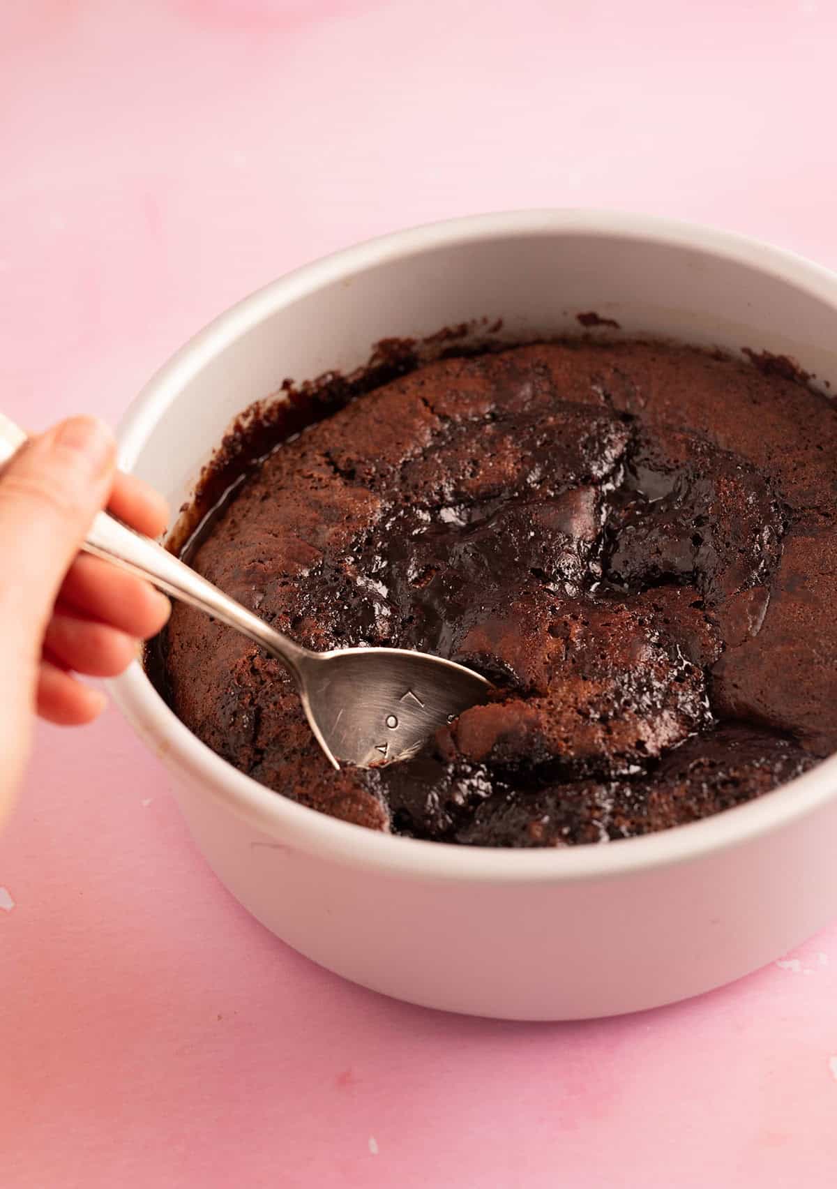 A beautiful chocolate self-saucing pudding with a spoon digging out a piece.