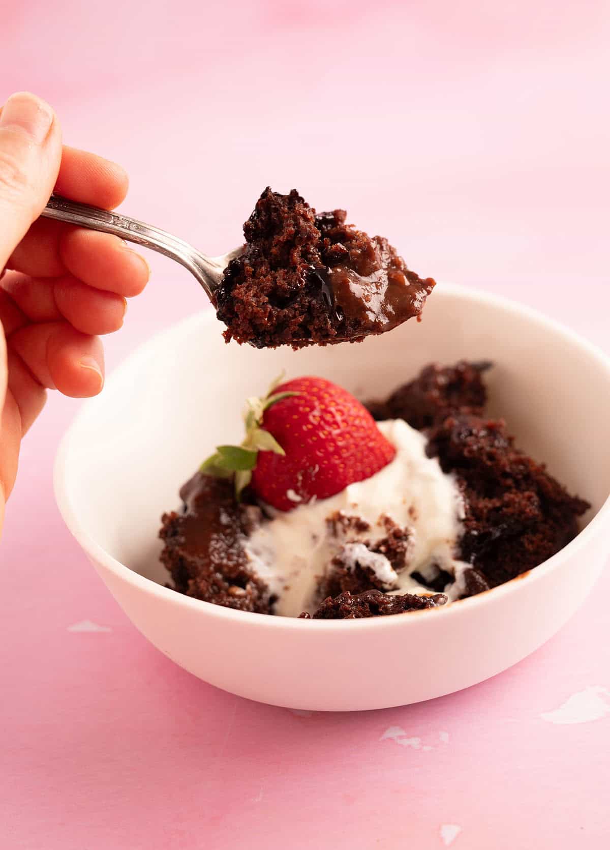 A beautiful bowl of pudding with cream and strawberries.