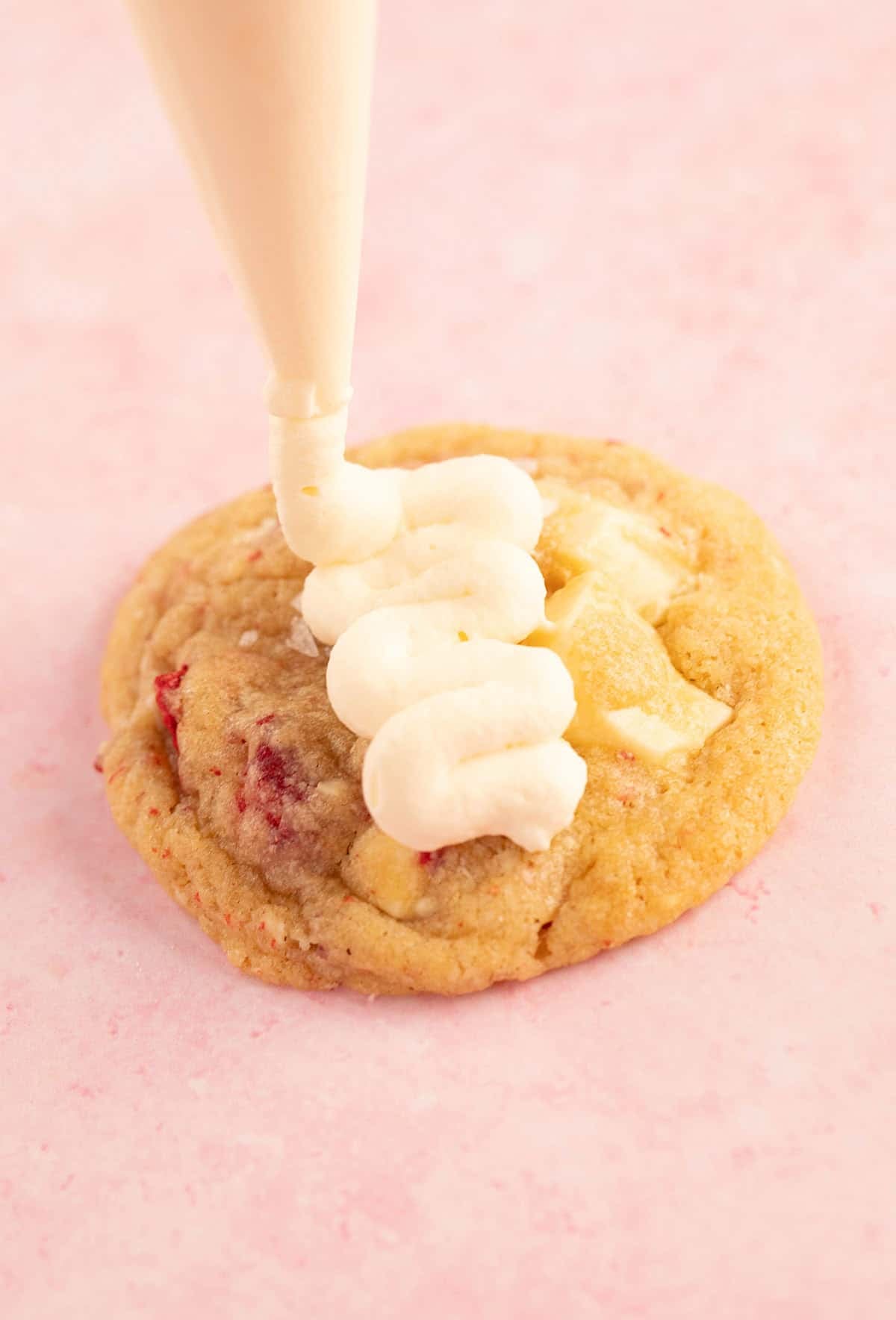 A beautiful strawberry cookie being frosted. 