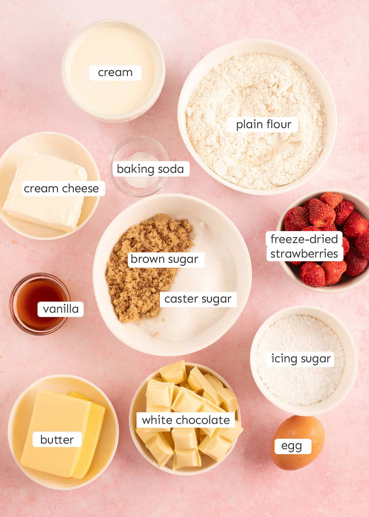 All the ingredients need to make Frosted Strawberries And Cream Cookies from scratch on a pink background. 