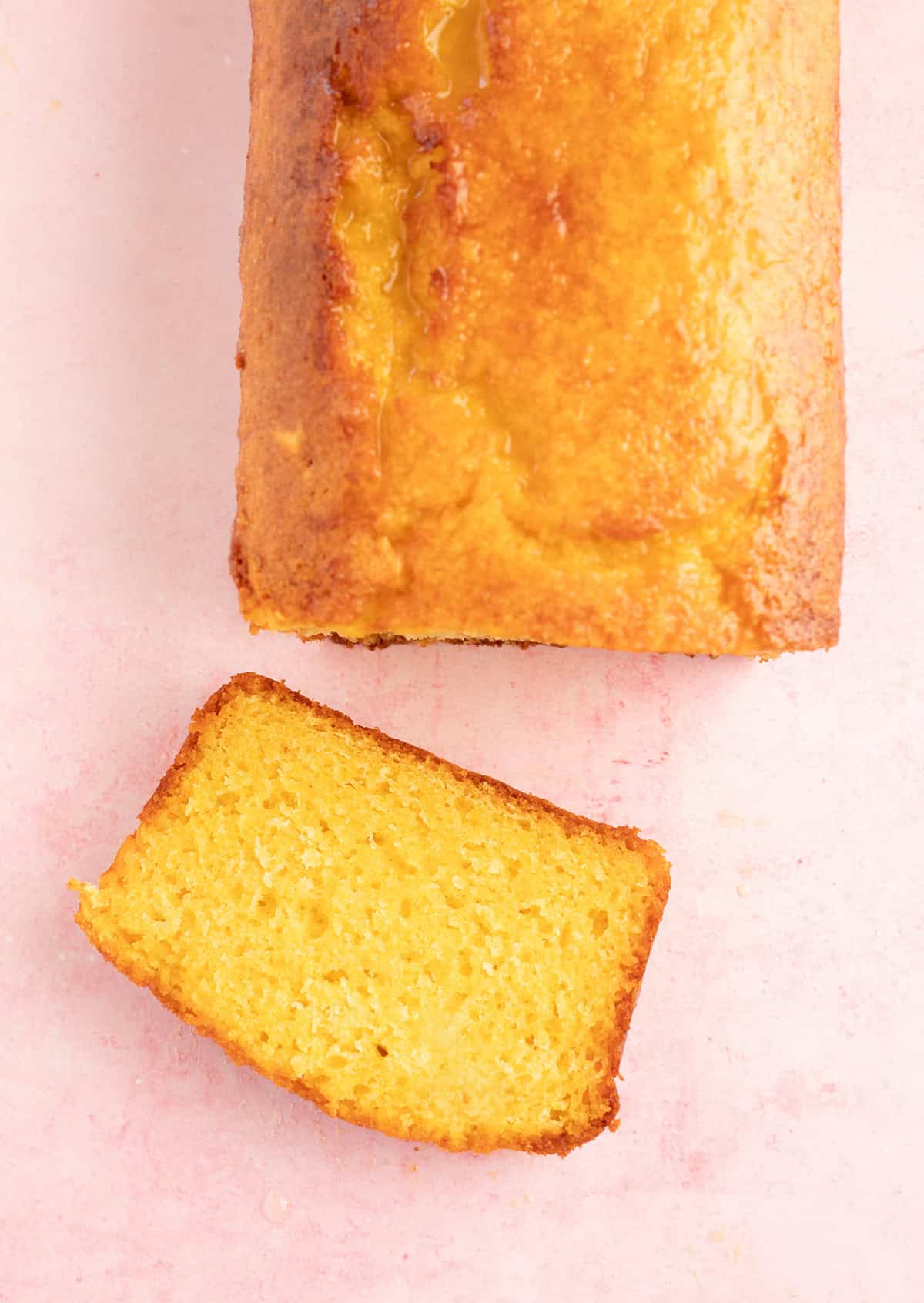 A slice of orange cake on a pink backdrop.