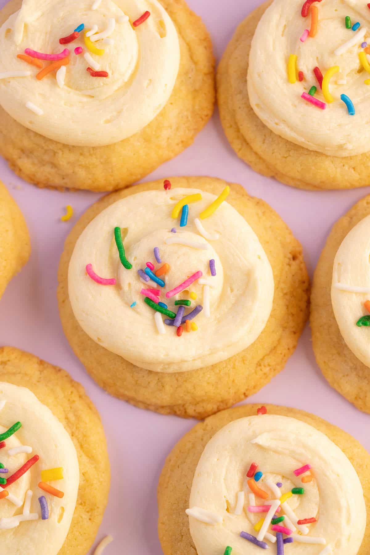 Top view of beautiful birthday cake frosted cookies on a purple backdrop.